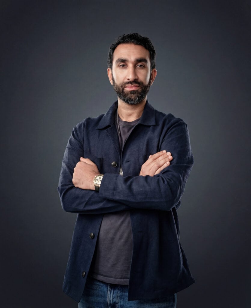 Manick Bhan standing confidently with arms crossed, showcasing professional branding.