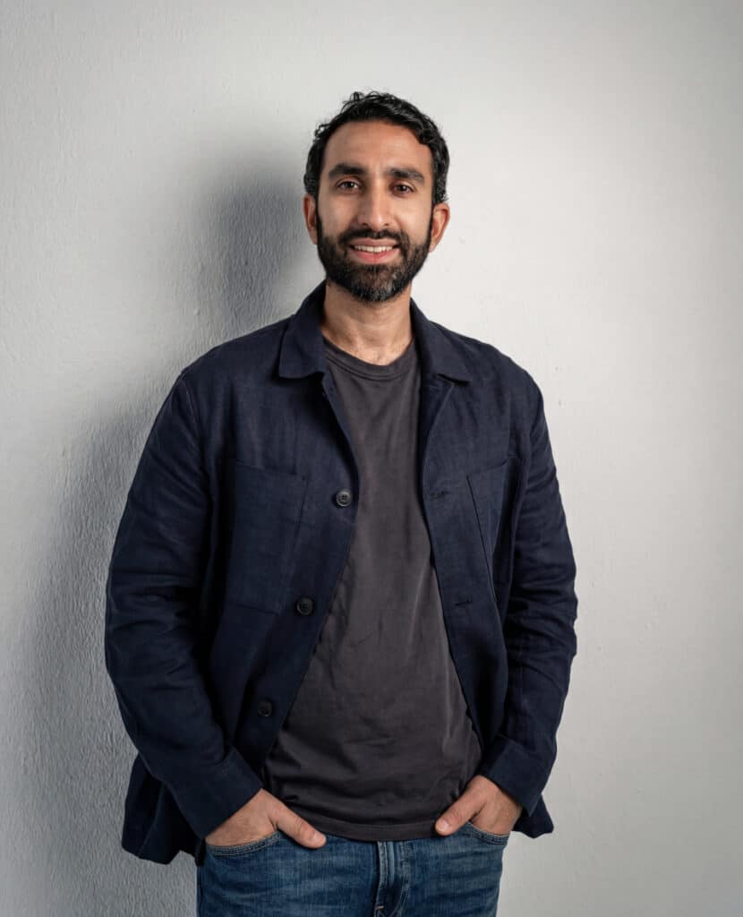 Manick Bhan smiling in casual attire for brand identity.